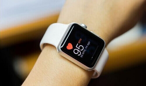 Foco em smartwatch preso ao pulso medindo os batimentos cardíacos.