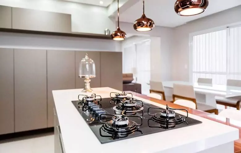 Abertura do post sobre o melhor cooktop: Cooktop preto instalado em balcão branco de cozinha estilo americana.